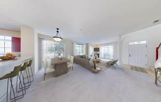 A well-lit, spacious living room with a dining area and a kitchen in the background.