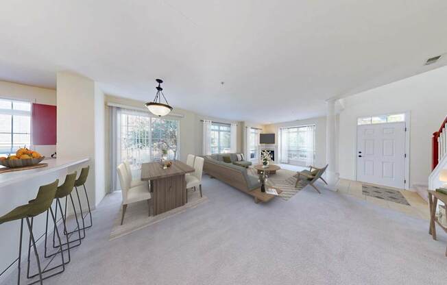 A well-lit, spacious living room with a dining area and a kitchen in the background.