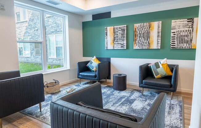 A living room with a black couch and a grey rug.