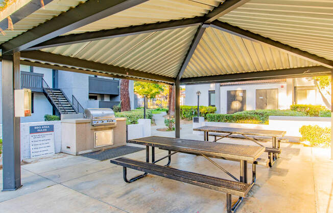 a patio with picnic tables and a grill outside of a building