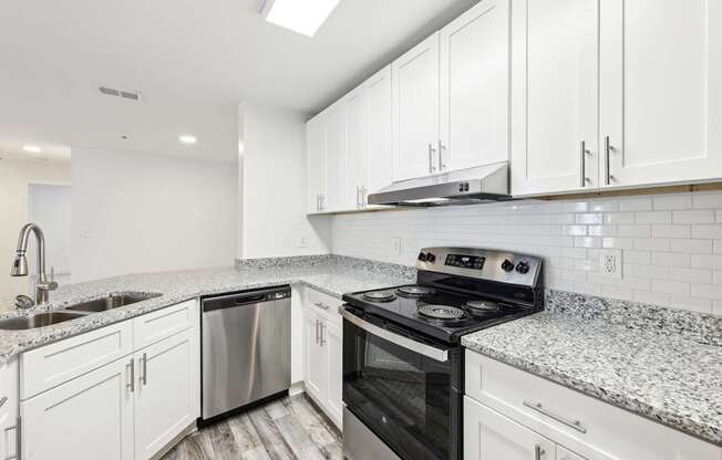 A kitchen with stainless steel appliances, white cabinets and a granite countertop.
