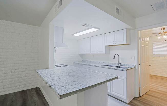 A kitchen with white cabinets and a marble countertop.