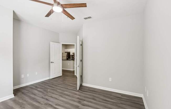 A room with a ceiling fan and a doorway leading to another room.