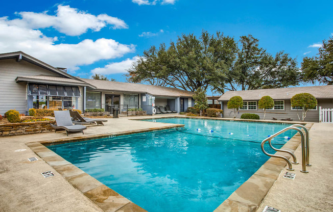 a swimming pool with lounge chairs and a house in the background