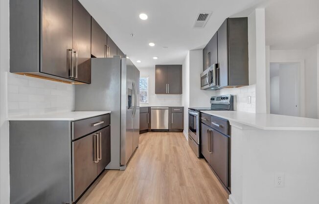 a large kitchen with stainless steel appliances and white counter tops