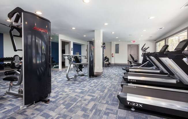 a gym with treadmills and other exercise equipment in a building with white ceilings