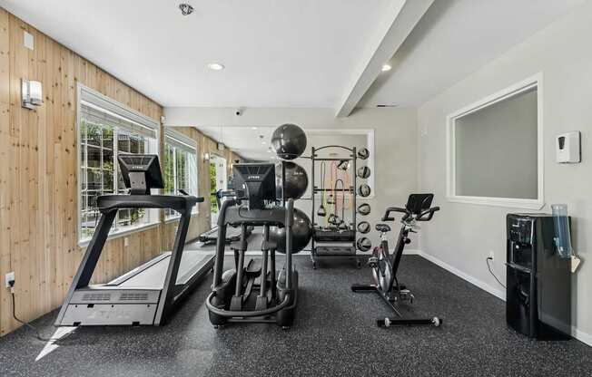 A home gym with a treadmill, elliptical trainer, and weights.