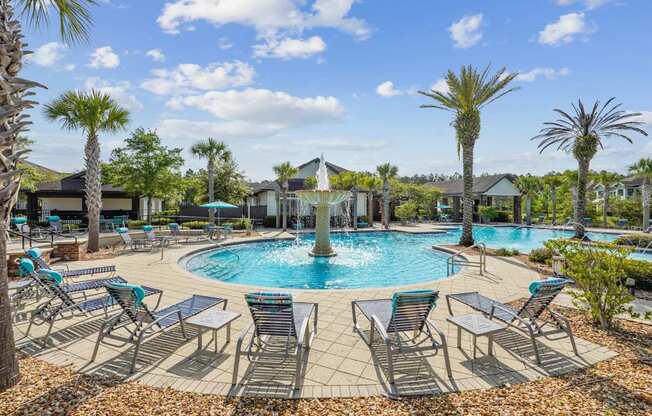 A pool surrounded by palm trees and lounge chairs.