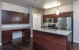 A kitchen with dark wood cabinets and a granite countertop.