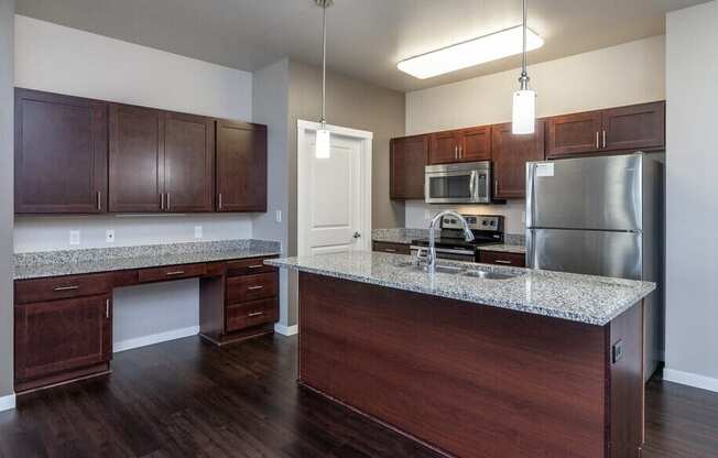 A kitchen with dark wood cabinets and a granite countertop.