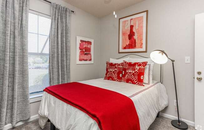 a bedroom with a red and white bed and a window