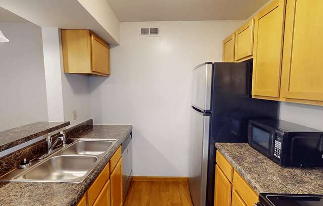 A kitchen with a black fridge and wooden cabinets.