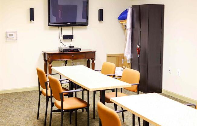 A conference room with a table, chairs, and a television.