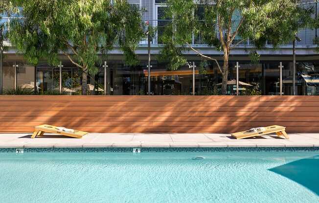 A pool with a wooden deck and sun loungers.