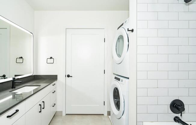Bathroom with a clean-lined vanity, integrated lighting, and in-home washer and dryer designed for comfort and everyday ease.