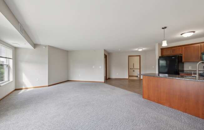 a spacious living room with a kitchen and a carpeted floor