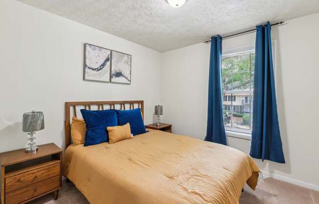 A bedroom with a bed, nightstand, and window.