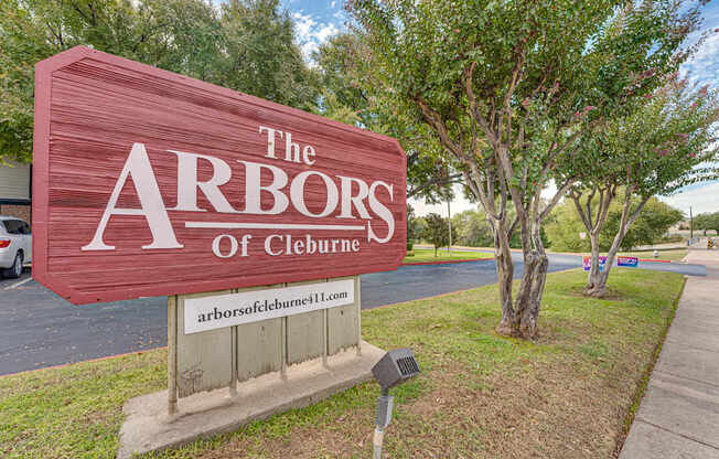 A sign that says "The Arbors of Cleburne" is in front of some trees.