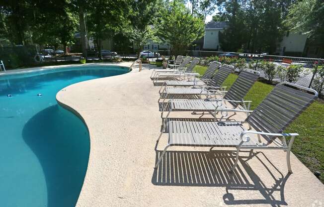 a row of chaise lounge chairs next to a swimming pool