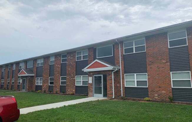 an apartment building with a red car parked in front of it