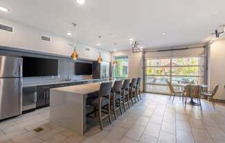 a kitchen with a long bar and chairs in front of a table