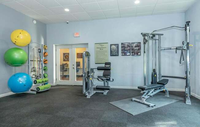 A gym with a variety of equipment including a leg press machine, a bench press, and a squat rack.
