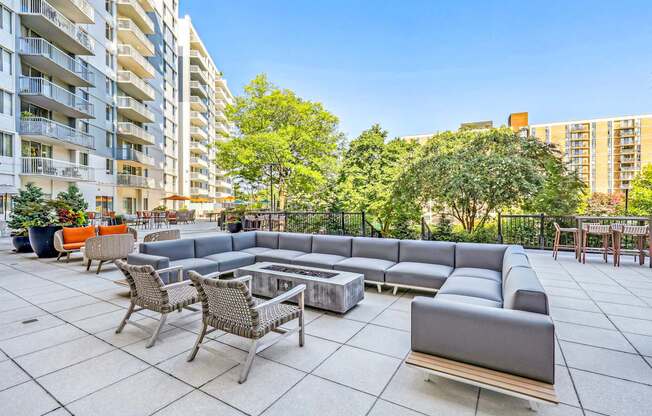 A patio with a grey sofa, chairs and a coffee table.