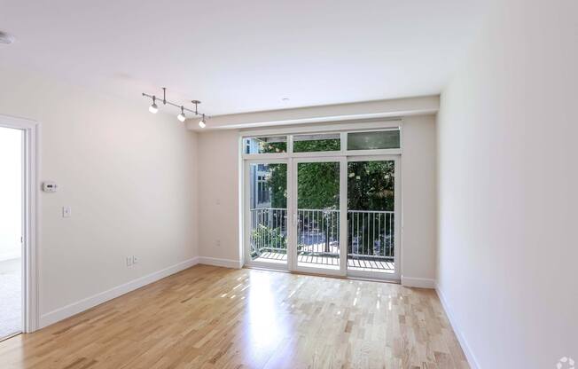 A spacious living room with a sliding glass door leading to a balcony at 7 Cameron Apartments, Massachusetts, 02140