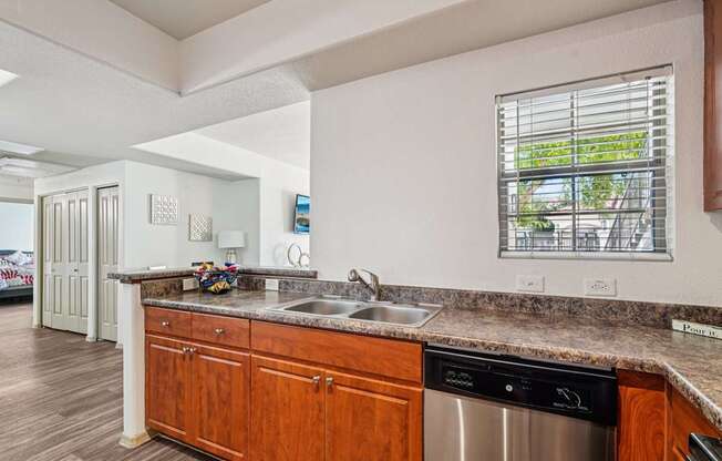 A kitchen with a stainless steel dishwasher and wooden cabinets.