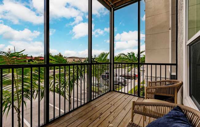a balcony with two chairs and a view of a palm tree