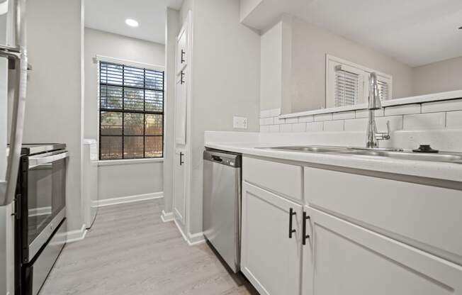 a kitchen with white cabinets and a window