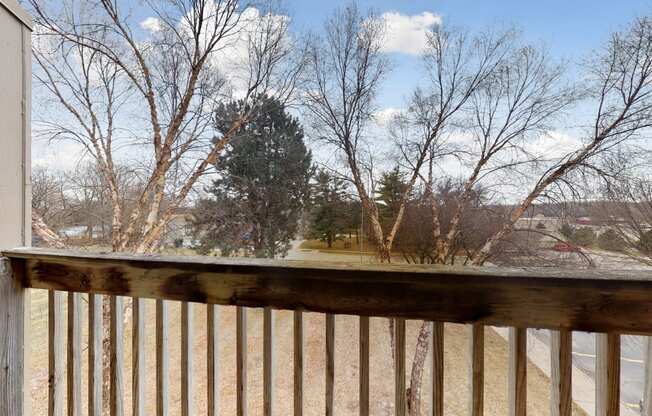 the view from the deck of a house overlooking a yard and trees