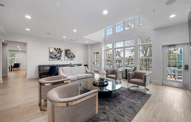 A modern living room with a glass table and grey chairs.