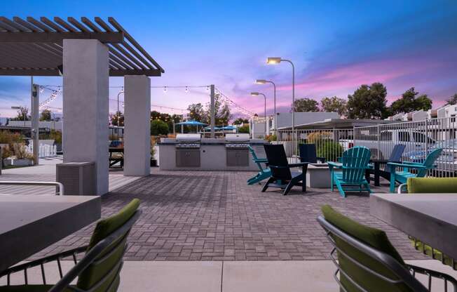 a patio with chairs and a grill at dusk