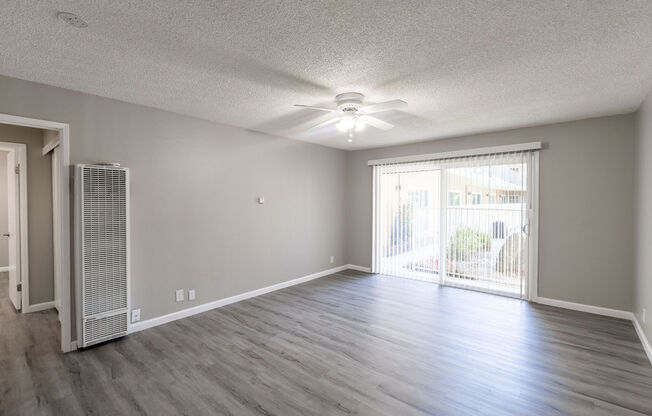 an empty living room with a ceiling fan and a window