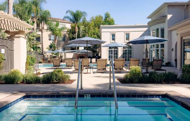 A spa and pool with a lounge chairs and umbrellas
