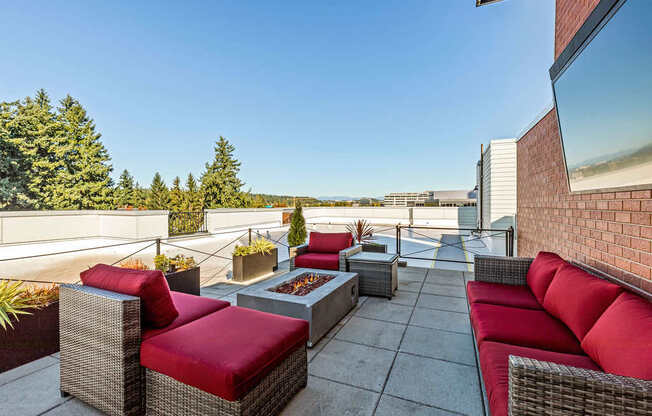A patio with red cushions and grey wicker furniture.