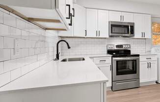 an empty kitchen with white cabinets and a white counter top
