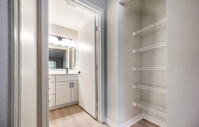 A white pantry with a door open to a bathroom.