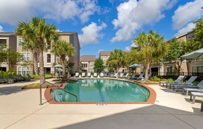 a swimming pool with palm trees in front of a building at Summerwind, Pearland