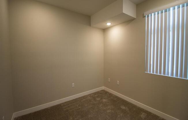 bedroom with a large window and a carpeted floor at Loma Villas Apartments, San Bernardino, CA