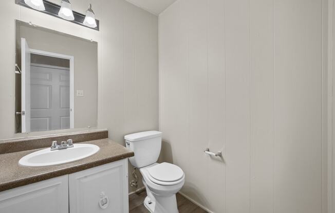 a bathroom with a toilet and a sink and a mirror at Brookside Apartments, Hewitt, TX, 76643