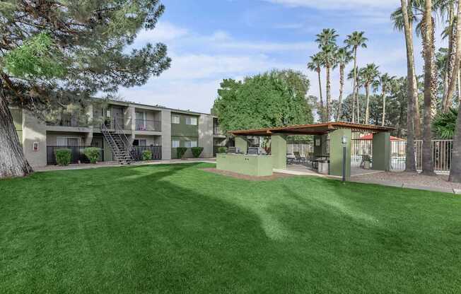 A grassy area in front of a building with palm trees in the background.
