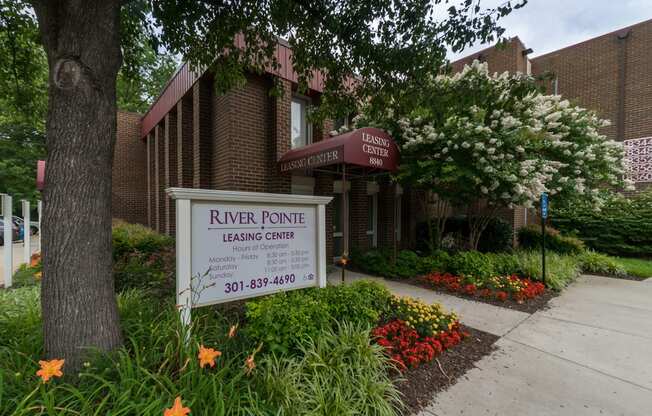 A leasing center named River Pointe is surrounded by greenery and flowers.