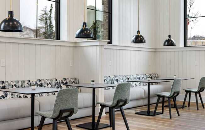 A white couch with a black and white patterned cushion sits under a row of hanging lights.