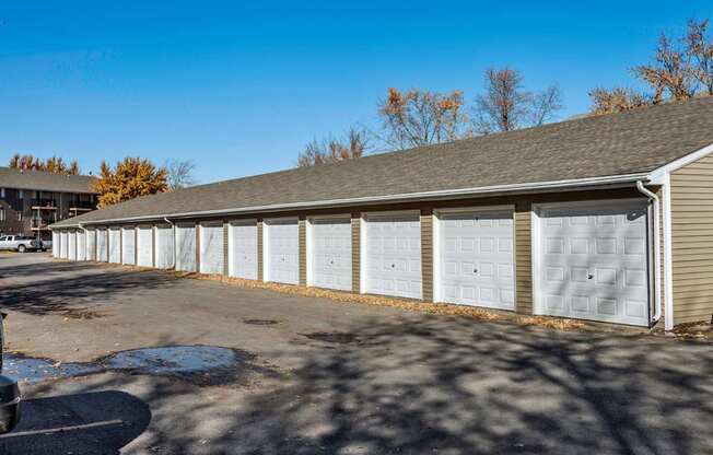 A long building with a grey roof and white garage doors at Sutton Hill Apartments, Des Moines, IA