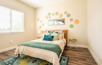 Model bedroom is furnished with a large bed and 2 nightstands at Village Greens of Queen Creek