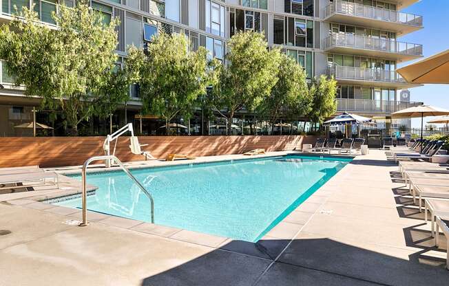 A swimming pool in front of a building with trees.