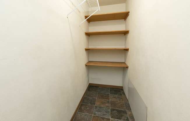 a walk in closet with shelves and a white wall. Fargo, ND Islander Apartments