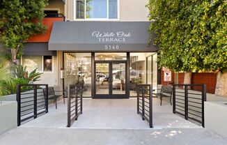 The front of a white oak terrace building with a black gate.